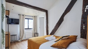 A bedroom with a bed, a TV, a window with curtains, and a wooden floor. - Apartment AC 2 Bedrooms Le Marais Beaubourg (Paris)