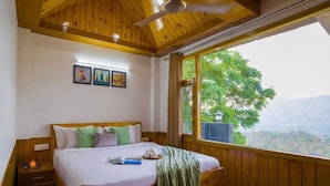 A wooden-framed bedroom with a large bed, a nightstand, and a window offering a view of greenery and mountains. - The Castle Villa Hill View kasauli (Kasauli)