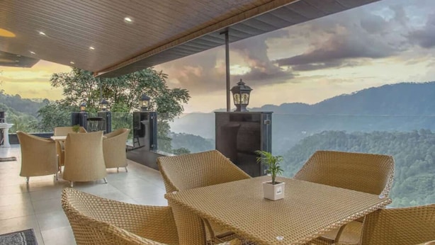 A spacious outdoor seating area with wicker furniture and a view of a mountainous landscape. - The Castle Villa Hill View kasauli (Kasauli)