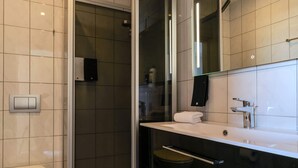 A modern bathroom with a glass-enclosed shower, a toilet, a sink, and a mirror.