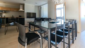 A modern kitchen with a dining area, including a glass table and black chairs.