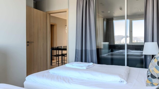 A hotel room with two beds, a desk, and a view of the city.