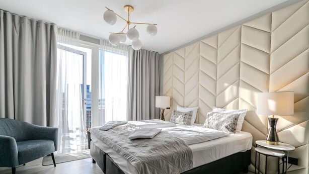 Ein modernes Hotelzimmer mit Bett, Sessel, Lampe und Blick ins Freie.