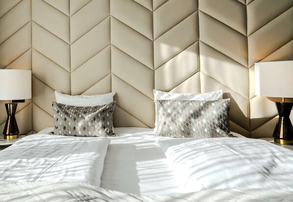 Un lit avec une tête de lit à motifs géométriques, deux lampes de chevet et des coussins à motifs.