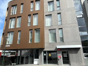 Ein modernes Hotel mit einer braun und grau gestalteten Fassade, großen Fenstern und einem gut sichtbaren Eingang mit einem Schild.