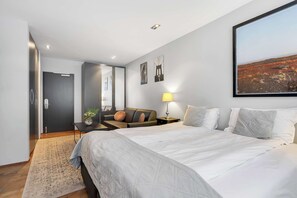 Ein modernes Hotelzimmer mit einem großen Bett, einem Schreibtisch mit Lampe, einer Couch und einem Bild an der Wand.