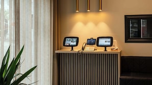 A reception desk with two monitors, a phone, and a circular light fixture above. - Midtown Reykjavik - Standard Double or Twin Room (Reykjavík)