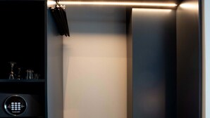 Un armari modern amb una banca integrada, un panell de control i una prateleira amb gots.