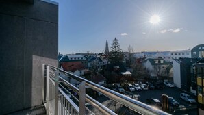A view from a balcony overlooking a parking lot with cars and buildings, under a clear sky with the sun shining. - Midtown Reykjavik - Double Room with Balcony (Reykjavík)