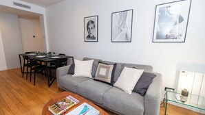 A modern living room with a grey sofa, a wooden coffee table, and a dining area with a black table and chairs. - Sublim Apartment 2 Bedrooms Center of Paris (Paris)