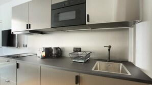 A modern kitchen with stainless steel appliances, a built-in oven, and a sink. - Sublim Apartment 2 Bedrooms Center of Paris (Paris)