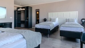 A hotel room with two beds, a desk, a wardrobe, and a mirror.