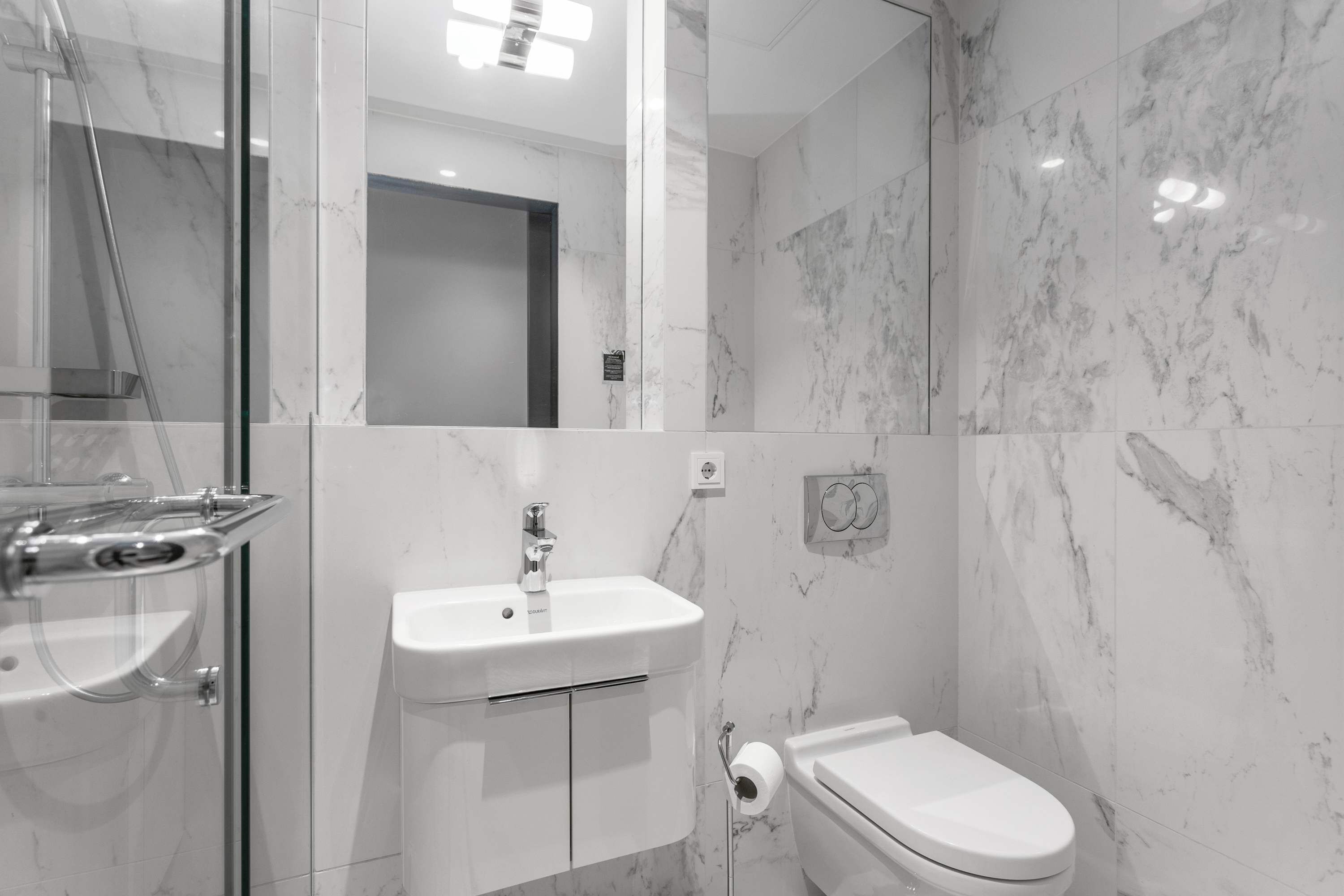 Une salle de bain moderne avec une douche à parois de verre, un lavabo blanc et des toilettes.