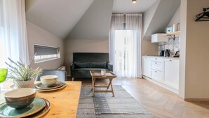 Moderni keittiö, jossa on valkoiset kaapit, musta työtaso ja sisäänrakennettu uuni.