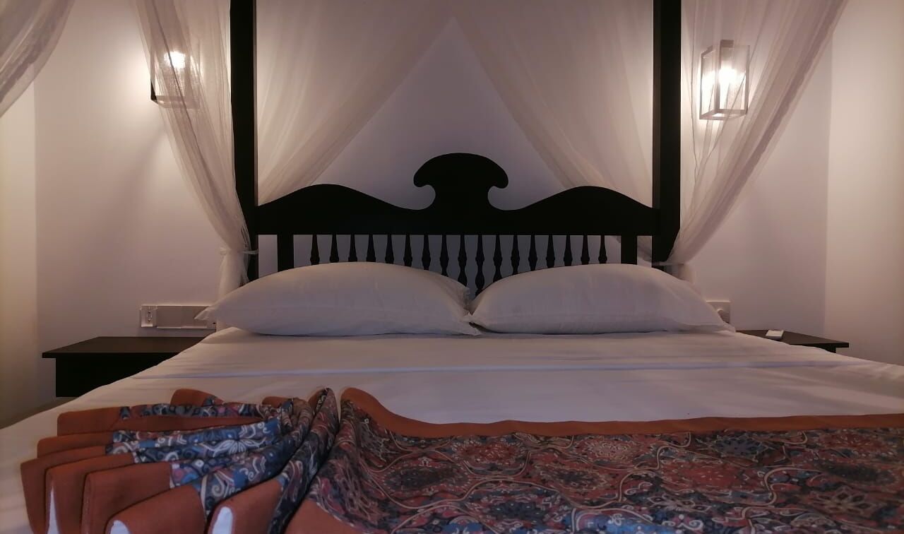 Una cama con dosel, dos mesitas de noche y una colcha estampada.