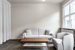 En minimalistisk stue med en lysegrå sofa, et træbord og en grå lænestol.