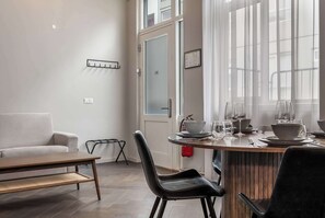 Et moderne spiseområde med et træbord, sorte stole og en hvid sofa.