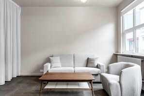 Una sala de estar minimalista con un sof á de color gris claro, una mesa de centro de madera y un sillón gris.