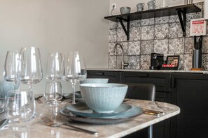 A kitchen with a tiled backsplash, a coffee machine, and a sign on the wall.