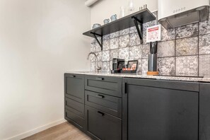 A kitchen with dark cabinets, a stainless steel sink, and a tiled backsplash.