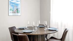 Un comedor con una mesa redonda, cuatro sillas y un cuadro en la pared.