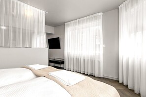 A hotel room with a bed, a TV mounted on the wall, and sheer curtains. - Swan Superior Studio Main Center (Reykjavík)