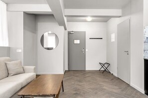 A modern living room with a sofa, a wooden coffee table, a round mirror, and a grey door. - Swan Superior Studio Main Center (Reykjavík)