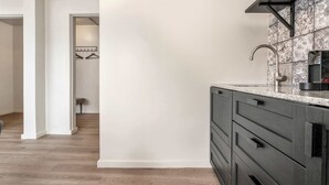 A kitchen with a modern design, featuring a dark-colored cabinet, a stainless steel faucet, and patterned backsplash tiles. - Swan Superior Studio (Reykjavík)