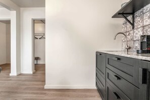 A kitchen with a modern design, featuring a dark-colored cabinet, a stainless steel faucet, and patterned backsplash tiles.