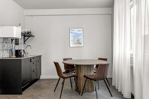 A modern kitchen with a central island, a dining table with chairs, and a framed picture on the wall.