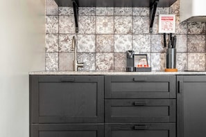 A kitchen with a tiled backsplash, a coffee machine, and a knife block.