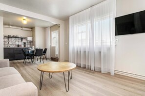 Un salon moderne avec une table ronde en bois, un canapé et un coin cuisine comprenant un ensemble de salle à manger.