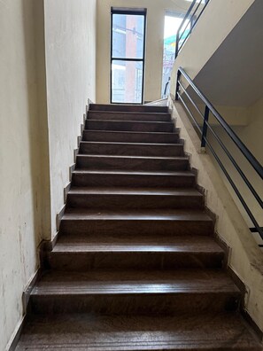 Un escalier muni d’une rampe, menant à une porte ouverte en haut.