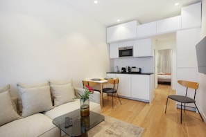 A compact living space with a kitchenette, a sofa, a dining area, and a TV mounted on the wall. - Montmorency Center of Paris Le Marais Beaubourg (Paris)
