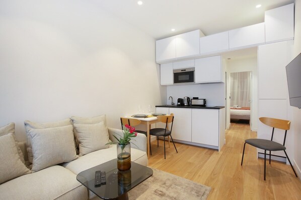A compact living space with a sofa, a dining table, and a kitchenette. - Montmorency Center of Paris Le Marais Beaubourg (Paris)