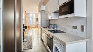 A modern kitchen with stainless steel appliances, a built-in oven, and a washing machine.