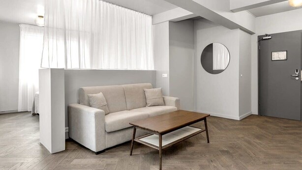 A modern living room with a sofa, a coffee table, and a door.