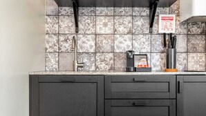 A kitchen with a tiled backsplash, a coffee machine, and a knife block.
