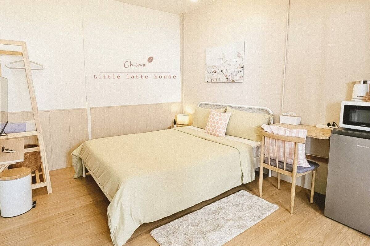Une chambre confortable avec un lit, une table de chevet, une lampe et une petite kitchenette.