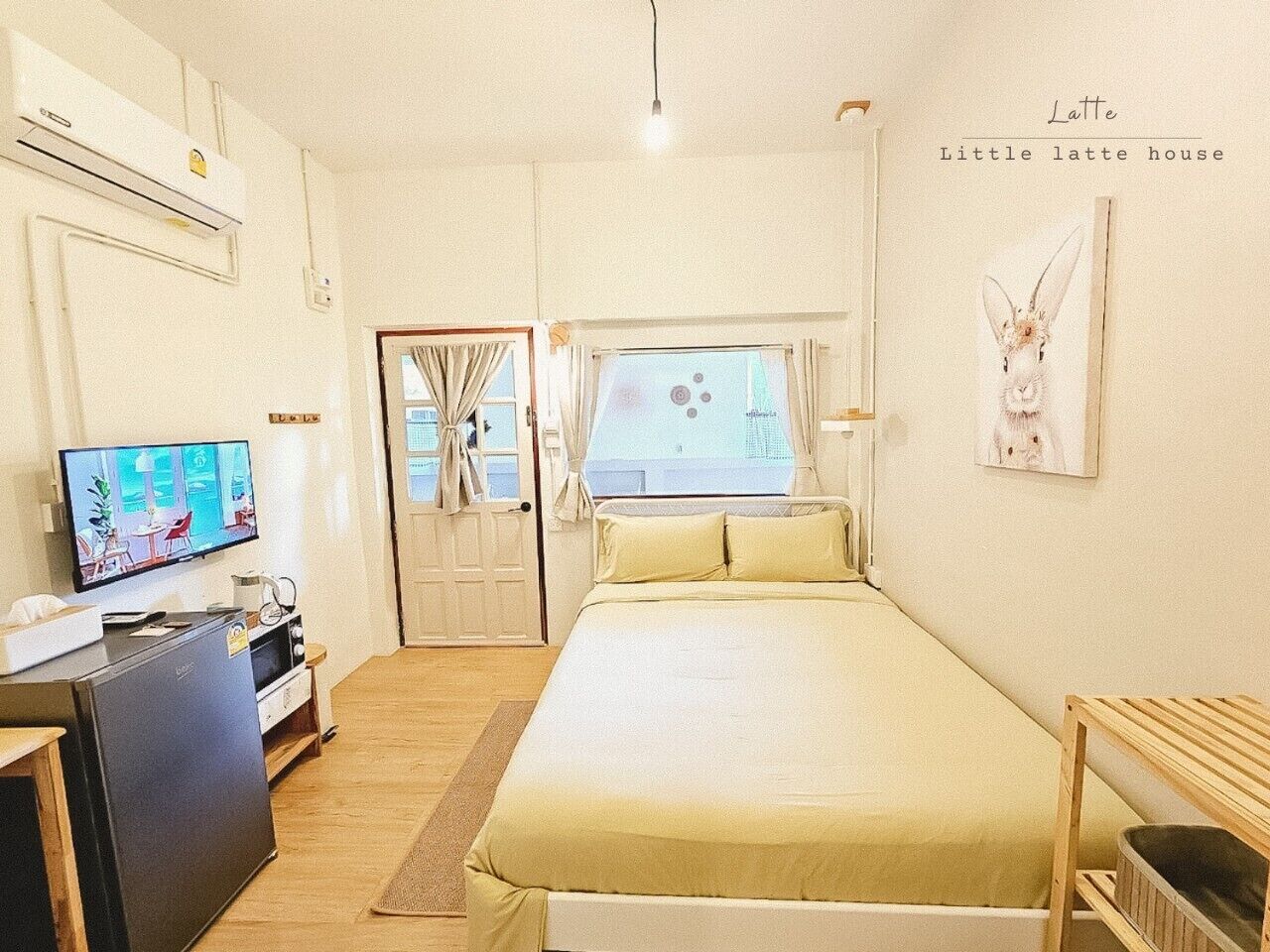 A cozy room with a bed, a TV, a desk, and a window with curtains.