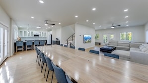 A spacious living area with a large wooden dining table, a sofa, and a kitchen in the background. - Jack–Modern 4-Level Luxury Retreat in Innsbruck (Helen)