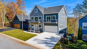 A two-story residential house with a front garage, a covered porch, and a well-maintained lawn. - Jack–Modern 4-Level Luxury Retreat in Innsbruck (Helen)