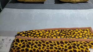Un letto con testiera imbottita, due cuscini e una coperta fantasia.