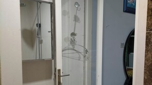 Un bagno con box doccia in vetro, un appendi asciugamani e uno specchio.
