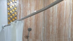 Un box doccia con tenda, soffione a mano e manopole a parete.