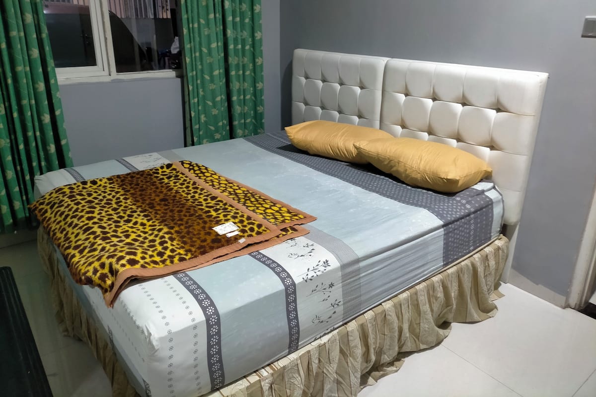 A bed with a patterned bedspread, a leopard print blanket, and two pillows.