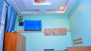 A room with a wooden cabinet, a television mounted on the wall, and a ceiling with recessed lighting. - DOM PRECIOUS LODGE (Dodoma)