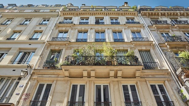 Un edificio de varios pisos de estilo arquitectónico clásico, con amplias ventanas y balcones con barandillas de hierro forjado.