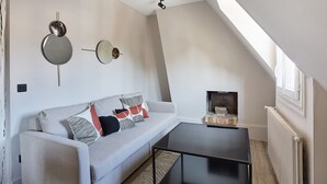 Una sala de estar moderna estilo loft con techo alto, un sofá gris con cojines estampados, una mesa de centro negra y una chimenea con revestimiento de ladrillo.
