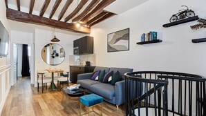 Ein modernes Wohnzimmer mit einem grauen Sofa, einem Essbereich mit einem runden Tisch und einer Treppe mit schwarzer Geländer.